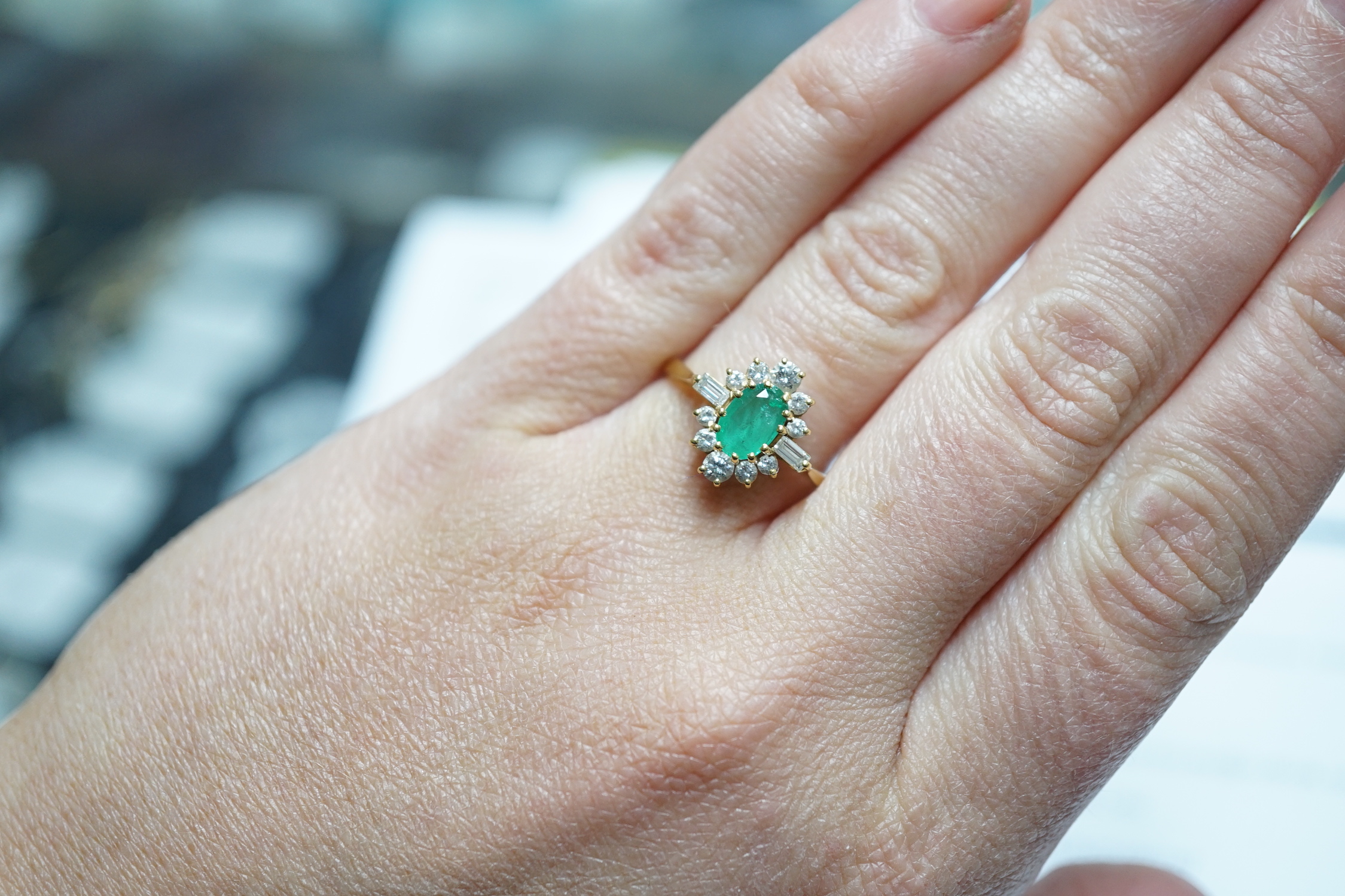 A modern 18ct gold, single stone oval cut emerald and round and baguette cut diamond cluster set ring, size P/Q, size 3 grams.